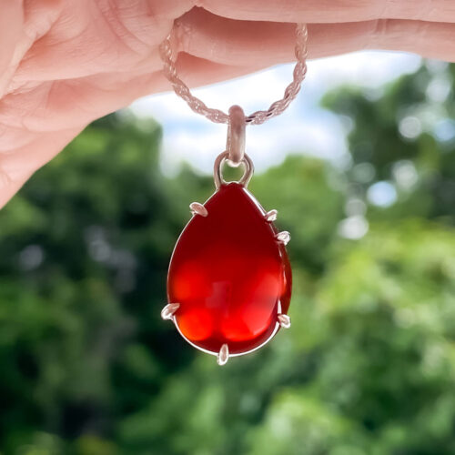 The Red Frangipani Pendant with Chain by INIZI has a surprise element.