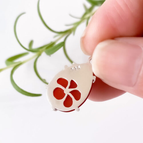 The Red Frangipani Pendant with Chain by INIZI has a surprise element.